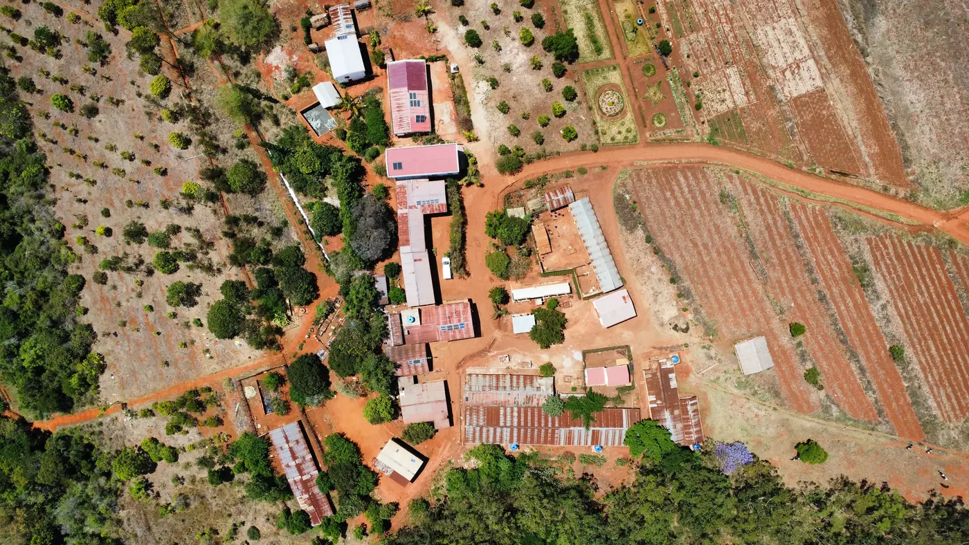 Vue aérienne à la verticale du domaine de Befoza : bâtiments, cultures et pistes de terre rouge
